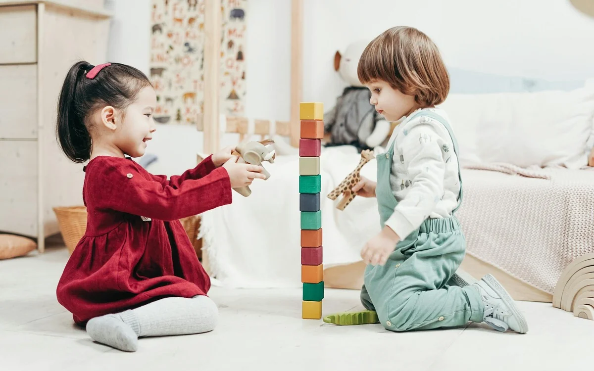 Niños jugando con bloques de construcción en actividad pedagógica creativa de primera infancia