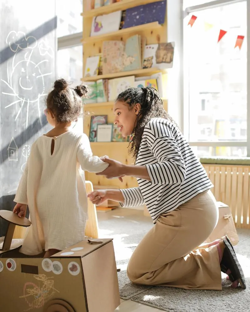 Educadora guiando a niña en actividad creativa, programa Técnico Laboral en Primera Infancia