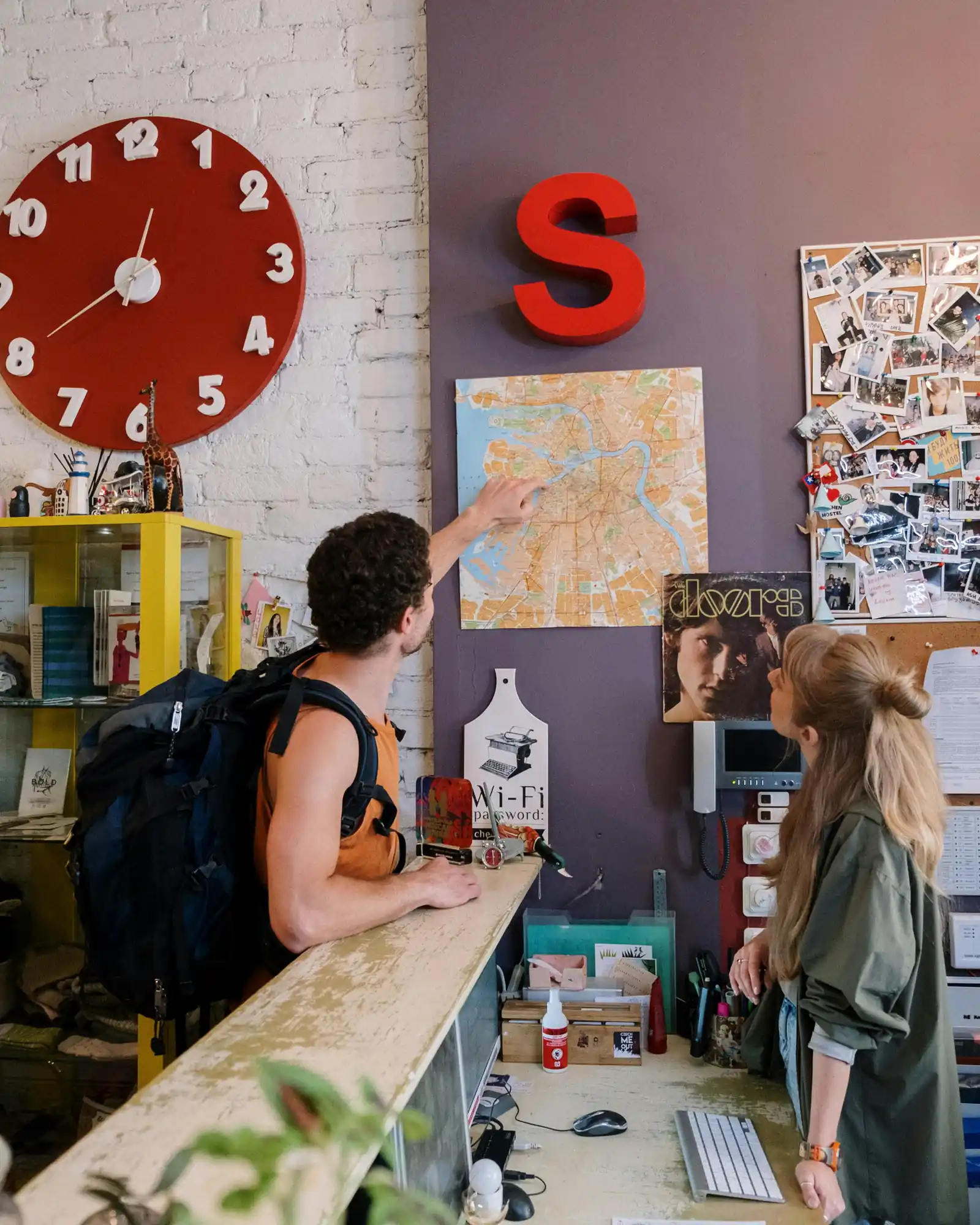 Backpacker en mostrador de hostel consultando mapa, programa Técnico Laboral en Agencia de Viajes y Turismo Córdoba