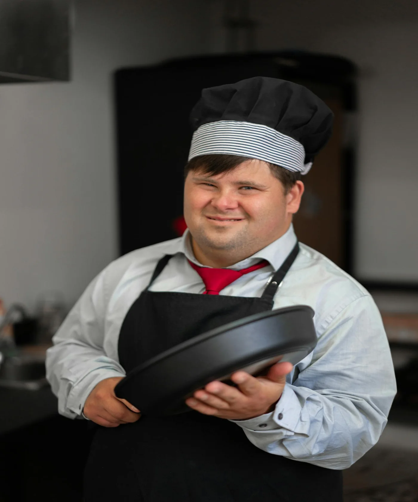 Chef sonriendo con sartén, orgullo culinario del programa Técnico Laboral en Cocina