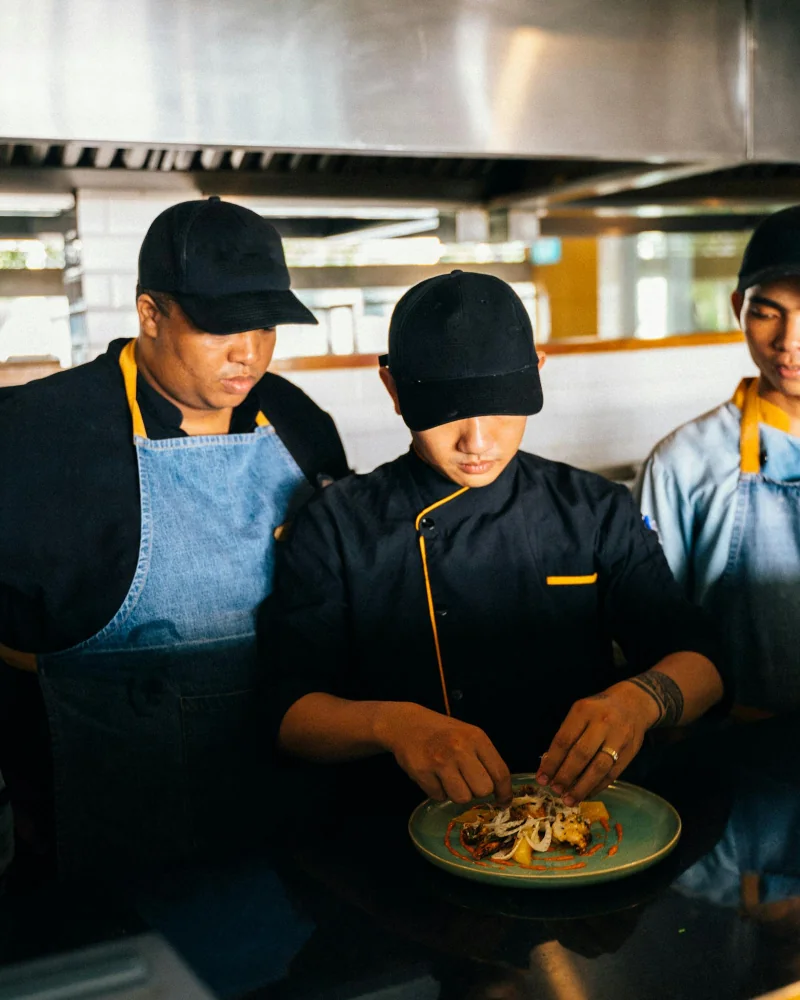 Tres chefs colaborando en cocina profesional, comunidad Libertadora Córdoba