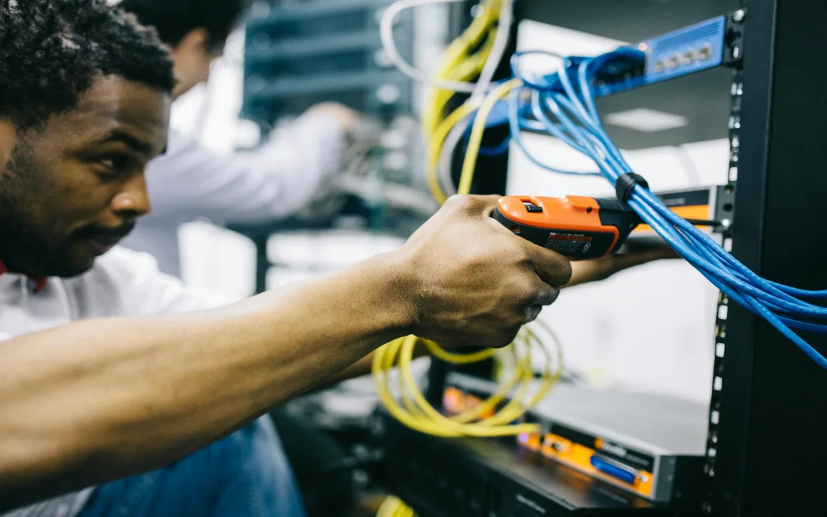 Técnico configurando switch y routers en cuarto de telecomunicaciones