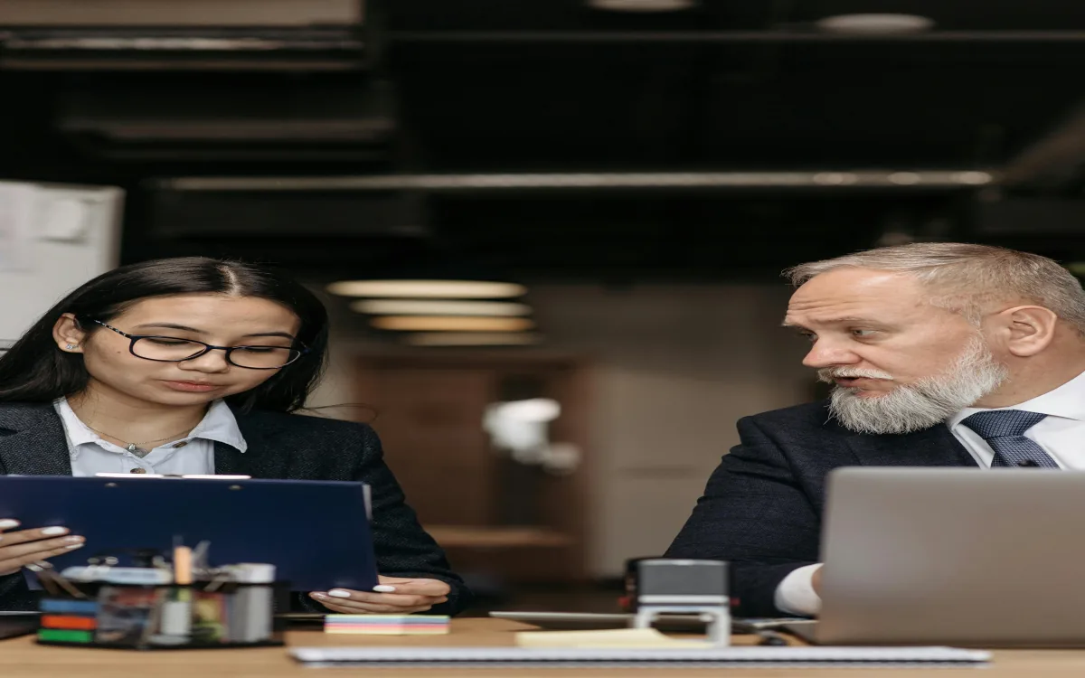 Profesionales corporativos discutiendo documentos en oficina moderna, etapa productiva del programa Técnico Laboral en Auxiliar del Talento Humano Córdoba