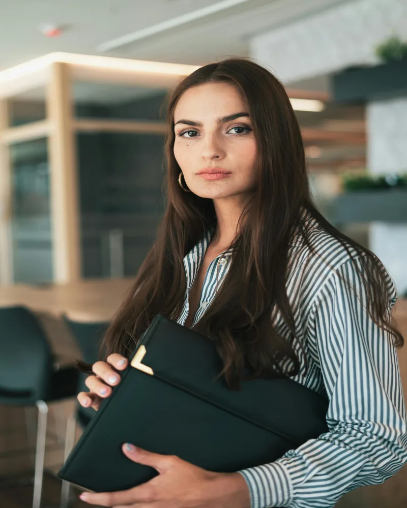 Mujer de negocios segura con documentos en oficina moderna, sello profesional del programa Técnico Laboral en Talento Humano